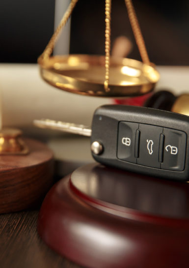 car accident lawyer Tinton Falls, NJ - Wooden referee hammer and car keys on the table-top view